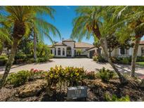 Stunning front exterior of a single-story home featuring a brick driveway and lush tropical landscaping at 7218 Teal Creek Gln, Lakewood Ranch, FL 34202