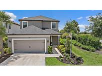 Beautiful two-story home featuring a two-car garage and meticulously landscaped front yard with tropical plants at 7743 Nightfall Ter, Sarasota, FL 34241