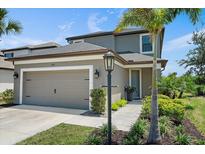 Charming two-story home with a gray exterior, a two-car garage, and a well-maintained, landscaped front yard at 7743 Nightfall Ter, Sarasota, FL 34241