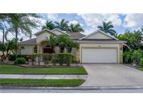 Well-maintained single-story home with a two-car garage, brick paved driveway, and lush tropical landscaping at 11592 57Th Street E Cir, Parrish, FL 34219