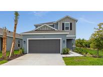 Charming two-story home featuring a modern gray facade, attached two-car garage, and well-maintained landscaping at 15001 Shady Palms Ln, Nokomis, FL 34275
