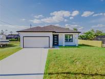 Charming single-story home featuring a clean white exterior, attached garage, and well-maintained lawn at 18182 Steele Ave, Port Charlotte, FL 33948