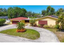 Charming yellow home features a circular driveway and well-manicured landscaping at 2410 Tanglewood Dr, Sarasota, FL 34239