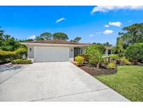 Charming single Gathering home boasts a well maintained front yard with mature tropical landscaping, and a two-car garage at 5603 Ravenwood Dr, Sarasota, FL 34243