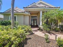 Attractive front exterior showcasing lush landscaping, a tile roof, and a columned entrance at 6924 Cumberland Ter, Bradenton, FL 34201