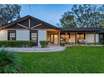 Charming home featuring blue front door and covered porch with inviting seating, nestled in lush landscaping at twilight at 7016 Dusty Rd, Riverview, FL 33569