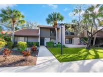 Charming home exterior featuring lush landscaping, mature palm trees, and a well-maintained lawn at 928 Sunridge Dr # F2, Sarasota, FL 34234