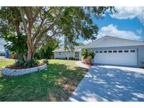 Charming single-story home with a well-manicured lawn, mature trees, and a spacious driveway leading to a two-car garage at 1896 Mova St, Sarasota, FL 34231