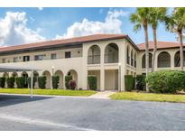 Beige two-story condominium building with arched entryways, red tile roof, trimmed bushes, and black parking lot at 3690 Pinecrest St # 114, Sarasota, FL 34232