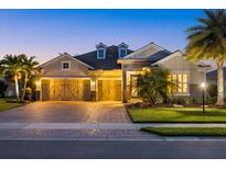 Elegant single-Gathering home with a three-car garage, lush landscaping, and a paver driveway at dusk at 3808 Eastham Ln, Bradenton, FL 34211