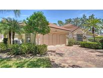 Charming single-story home with a well-manicured lawn, mature trees, and a brick driveway leading to a two-car garage at 3984 Lyndhurst Ct, Sarasota, FL 34235