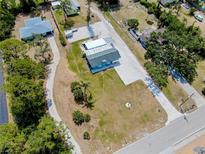 An aerial view captures a house with a spacious driveway, complemented by a grassy yard, mature trees and a serene neighborhood atmosphere at 612 Shore Rd, Nokomis, FL 34275
