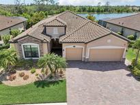 Stunning Mediterranean style home with lush landscaping, brick driveway and serene lake view at 13587 Vancanza Dr, Venice, FL 34293