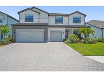 Beautiful two-story home featuring a brick driveway, three-car garage, and tropical landscaping at 16434 Slate Pl, Bradenton, FL 34211