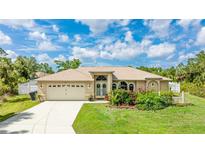 Charming single-story home featuring a well-manicured lawn, mature landscaping, and an attached two-car garage at 1667 Oakland Rd, North Port, FL 34286