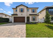 Stunning two-story home featuring a brick driveway, attached garage, and lush green lawn at 3113 W Nassau St, Tampa, FL 33607