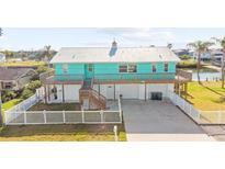 Charming waterfront home with a metal roof, a large deck, and a white picket fence at 3416 Crape Myrtle Dr, Hernando Beach, FL 34607