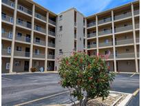 Exterior of condo building showcases well-maintained landscaping with blooming flowers and a patriotic American flag at 3744 Lake Bayshore Dr # K-503, Bradenton, FL 34205