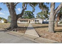 Inviting single-story home featuring mature trees, decorative stone accents and a quaint front entrance at 3941 Pin Oaks St, Sarasota, FL 34232