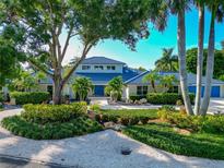 Beautiful home featuring lush landscaping, palm trees, and a striking blue tiled roof at 4307 Camino Real, Sarasota, FL 34231