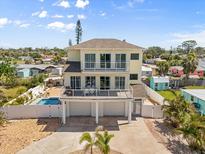 Stunning three-story coastal home featuring double balconies, a pool, and lush tropical landscaping at 4717 Lemon Bay Dr, Venice, FL 34293