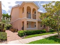 Inviting two-story townhome featuring a charming front porch and balcony, complemented by lush landscaping at 5388 Davini St, Sarasota, FL 34238
