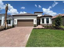 Beautiful single-story home featuring a brick-paved driveway, a brown two-car garage door, and well-manicured landscaping at 6203 Grandview Hill Ct, Bradenton, FL 34203