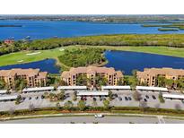 Stunning aerial view of condos with a golf course, a lake, covered parking and beautiful landscaping at 6509 Grand Estuary Trl # 203, Bradenton, FL 34212