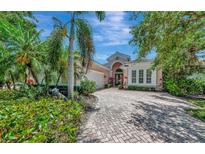 Elegant single-story home with lush landscaping, brick driveway, and a two-car garage at 7624 Boltons Ct, Bradenton, FL 34201