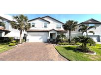 Charming two-story home with a brick driveway, lush landscaping, and a two-car garage at 13422 Flat Woods Ter, Bradenton, FL 34211