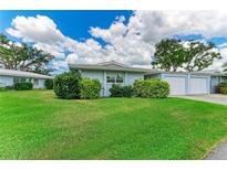 Charming single-story home featuring lush green lawn and landscaping, blue exterior, and an attached one-car garage at 1364 Westport Ln # 1403, Sarasota, FL 34232