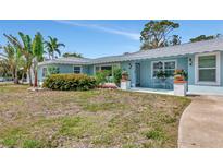 Charming blue home with tropical landscaping, inviting porch, and manicured front yard at 1722 Hazelwood St, Sarasota, FL 34231