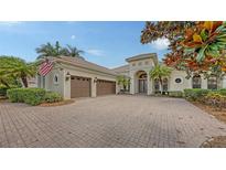 Stately home with a paver driveway, a three-car garage, and lush landscaping at 6919 Dominion Ln, Lakewood Ranch, FL 34202