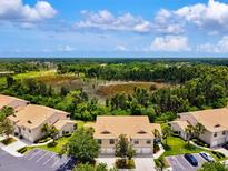 Beautiful aerial view of the townhomes with a large pond and lush green trees behind the homes at 7039 Strand Cir # 34-201, Bradenton, FL 34203