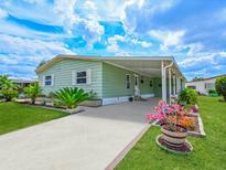 Charming single-story home featuring a covered carport, well-manicured lawn, and colorful flower beds at 8400 Princess Ct, Palmetto, FL 34221