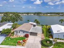 Charming waterfront home featuring lush landscaping and a covered carport on a sunny day at 8439 Imperial Cir, Palmetto, FL 34221