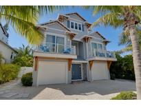 Coastal home featuring two-car garage, covered balconies, and tropical landscaping for a relaxing island lifestyle at 212 72Nd, Holmes Beach, FL 34217