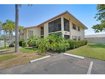 Well-maintained building exterior featuring lush landscaping, a private screened balcony, and ample parking at 2415 Bayshore Gardens Pkwy # 8, Bradenton, FL 34207