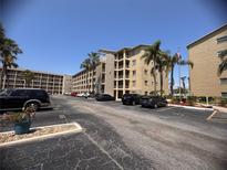 View of the tan building featuring multiple floors, palm trees, and plenty of parking spaces at 3647 Lake Bayshore Dr # 416, Bradenton, FL 34205