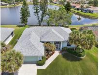 This aerial view showcases a home with a beautiful lake view, green lawn and mature palm trees at 5596 Sabal Trace Dr, North Port, FL 34287