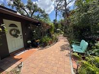 Inviting brick path leading to the front door with lush tropical landscaping and a quaint bench at 590 Artists Ave, Englewood, FL 34223