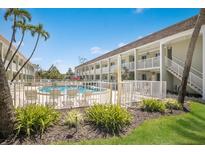 Exterior view of a community pool surrounded by lush landscaping and a multi-story condo building at 7100 Gulf Dr # 114, Holmes Beach, FL 34217