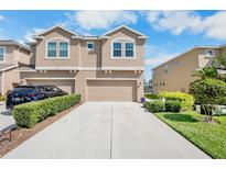 Charming two-story townhome featuring a concrete driveway, a two-car garage, and manicured landscaping at 11575 84Th Street E Cir # 104, Parrish, FL 34219