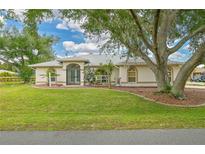 Charming single-story home with a lush green lawn, mature trees, and well-maintained landscaping at 2136 Bendway Dr, Port Charlotte, FL 33948