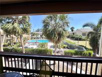Balcony view showcasing a refreshing community pool area surrounded by lush tropical palm trees at 3447 Clark Rd # 246, Sarasota, FL 34231