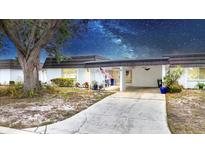 Charming single-story home featuring a covered carport and a welcoming front patio with decorative plants and an American flag at 3941 Glen Oaks E Dr # 32, Sarasota, FL 34232