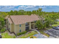 A charming, tan apartment building with well-kept landscaping, plenty of trees, and a blue sky background at 4009 Crockers Lake Blvd # 22, Sarasota, FL 34238
