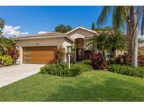 Charming home with a well-manicured lawn, lush landscaping, and a stylish wood garage door at 4435 Beauchamp Ct, Sarasota, FL 34243