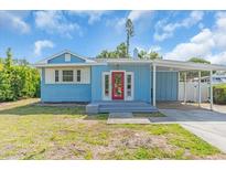 Charming single-story home with a light blue exterior, carport, and a welcoming red front door at 5012 Eastchester Dr, Sarasota, FL 34234