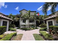 Beautiful condo exterior with lush tropical landscaping and brick paver walkway to the front door at 5685 Palmer Cir # 204, Lakewood Ranch, FL 34211